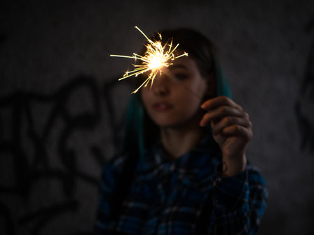 Portrait of model girl with blue hair looks with sparklers in their hands. Close up. Beautiful young...