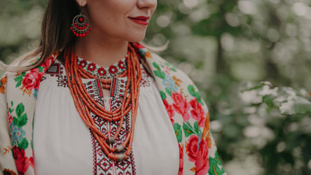 Pretty woman in traditional ukrainian jewelry necklace, dress, handkerchief and gerdan. Lady in national costume - vyshyvanka and ancient coral beads on forest nature backgroundの写真素材