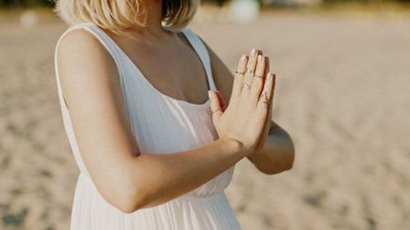 Praying meditating woman, reading mantras, directs thoughts, requests or gratitude to universe. Beach, morning near sea. Spirituality, religion, God concept.の写真素材