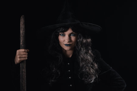 Portrait of black witch at night. Halloween masquerade costume, party decoration. Magic, classic hag