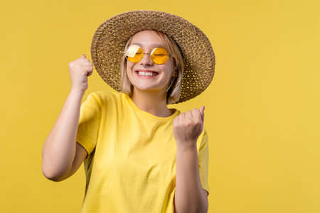Pretty woman shows triumph yes gesture of victory, she achieved result, goals. Girl glad, happy, surprised excited happy lady on yellow background. Jackpot concept.の写真素材