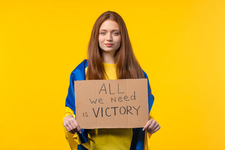 Ukrainian woman with cardboard All we need is victory on yellow background. Ukraine will win war. Democracy, liberty, demonstration, russian aggresion conceptの写真素材