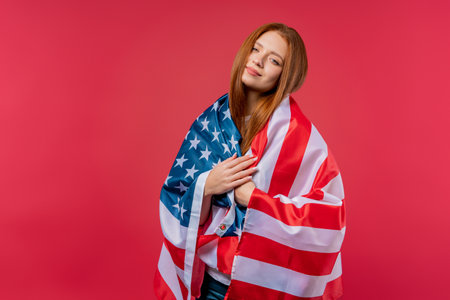 Smiling woman with national USA flag on pink background. American patriot, 4th of July - Independence day celebration, election, America, labor. US banner.の写真素材