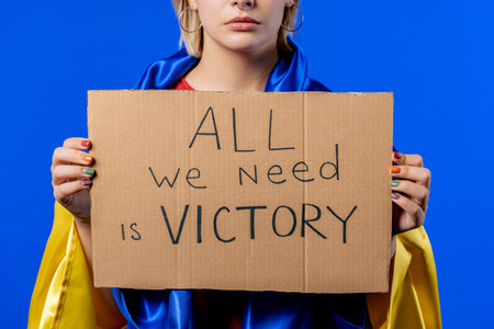 Ukrainian woman with cardboard All we need is victory on blue background.の写真素材