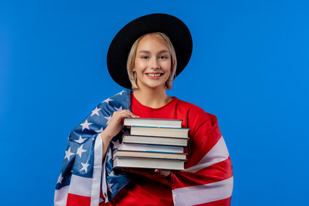 American woman student with stack of books on blue background. Education in USA.の写真素材
