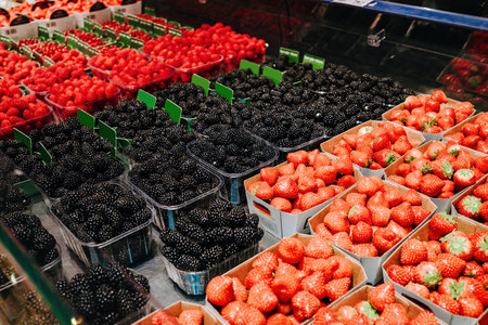 Lot of berries in supermarket. Sale of healthy product, strawberry, blackberry.