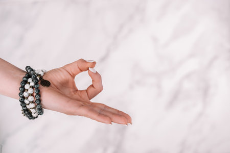 Om on white background. Female hand with mala beads bracelet. Woman meditating,の写真素材