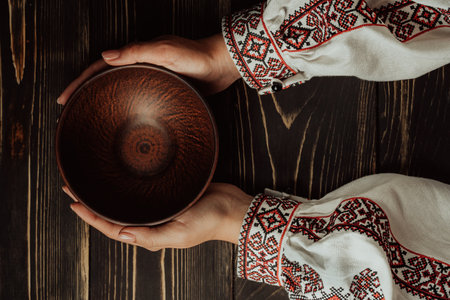 Female hands with empty ukrainian clay bowl on wooden table. Copy space.の写真素材