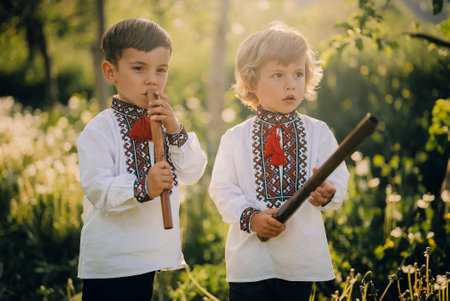 Little brothers boys playing woodwind wooden flute - ukrainian sopilka outdoorsの写真素材
