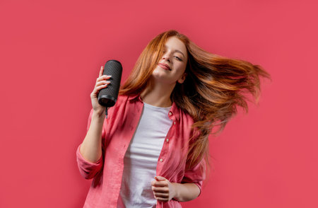 Young woman listening to music by wireless portable speaker, dancing rich hairの写真素材