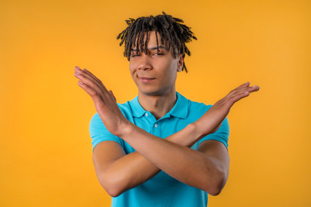 Serious man showing rejecting gesture by stop finger sign. don't play with me. Guy isolated on yellow background. high quality photoの写真素材