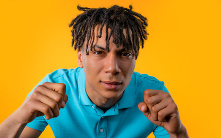 African man cannot believe eyes, squinting because cant anything, yellow background. Poor eyesight, vision problems. Young guy with long dreadlocks hairstyle.の写真素材