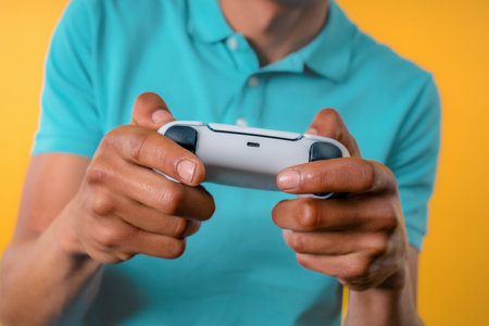 Young man playing video exciting game on Tv with joystick isolated on yellow studio background....