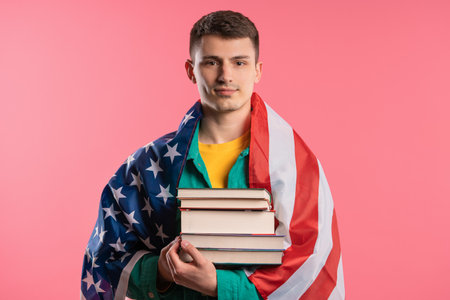 American student man student with stack of books pink background. Education USAの写真素材