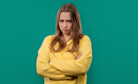 Offended young woman, arms crossed, feeling mad. Teen maximalism.Blue backgroundの写真素材