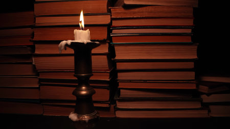 Candle in candlestick with old books, background in antique shop, bookstore.の写真素材