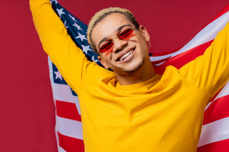 Happy man with national USA flag on red background. American patriot 4th of Julyの写真素材