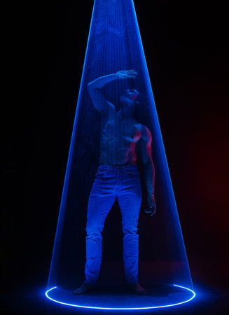 Sporty handsome muscular man portrait under colorful illumination, laser light