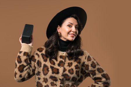 Pretty woman listening music by wireless portable speaker - sound system, beigeの写真素材