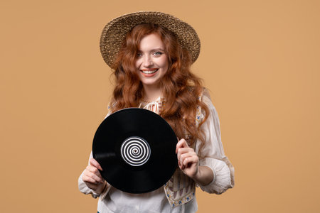 Pretty woman dancing with vinyl record disc on beige. Hobby, music lover, collection, nostalgia lifestyle.の写真素材