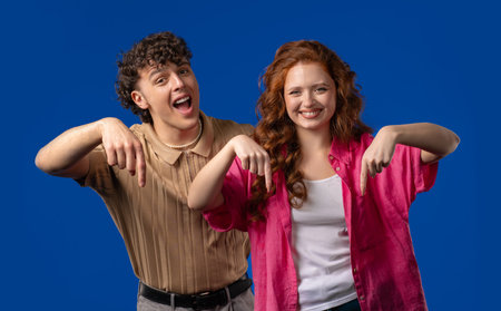 Young Couple Bloggers Pointing Down To Advertising Area. Click Subscribe Below