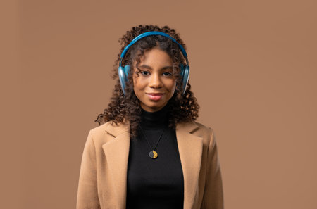 African Teenager Zoomer Girl Listening Music, Dancing With Headphones On Beigeの写真素材
