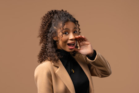 Attention, portrait of african young woman shouting,holding hand near open mouth