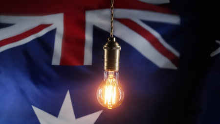 classic antique Edison Tungsten filament lamp on waving Australian flag background. Raising tariffs for electricity supply, bills, energy crisis in Australia.の写真素材