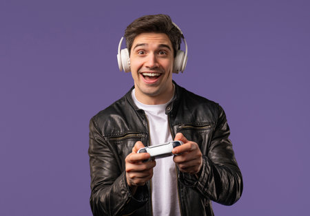 Excited gamer man playing online video game on console with gamepad on violet