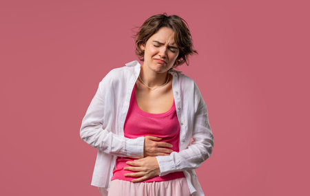 Young woman squeezing belly with hands. abdominal pain, suffering stomach acheの写真素材