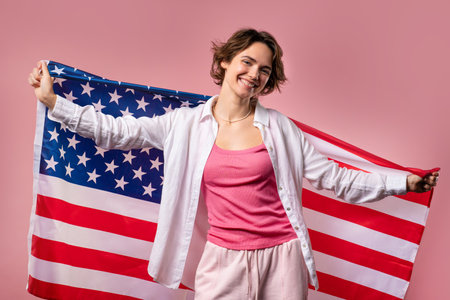 Smiling woman with national USA flag on pink background. American patriot, 4thの写真素材