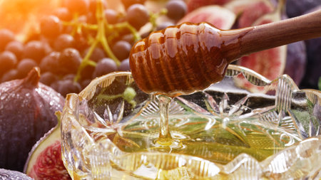 Organic honey flows from olive wood dipper stick spoon, tasty process. Amazing fruits - figs, grapes background. Still life.の写真素材
