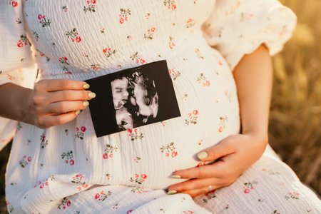Happy Mother Carrying Child, Expecting For Baby. Demonstrating Ultrasound Shot. Amazing Motherhood. Pregnant Woman in beautiful dressの写真素材