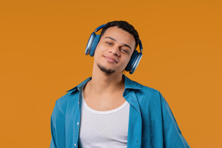 Positive mixed race man listening music, enjoying dance with modern headphonesの写真素材