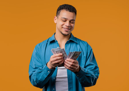 Rich african american man with Usd money on yellow background. Young Guy Or Student counting salary, scholarship payment. Jackpot, winの写真素材
