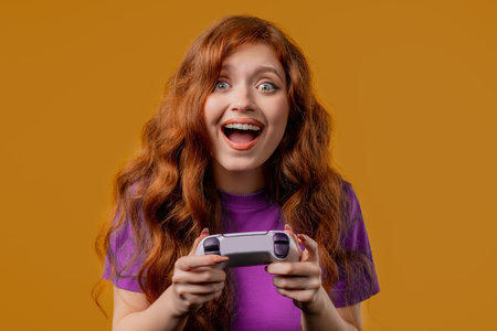 Young pretty woman playing, wins online video game console with gamepad, yellowの写真素材