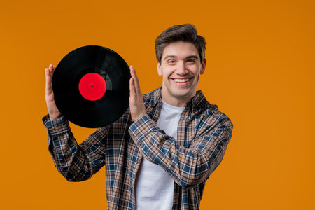 Stylish mature man with vinyl record disc on yellow. Hobby, music, collectionの写真素材