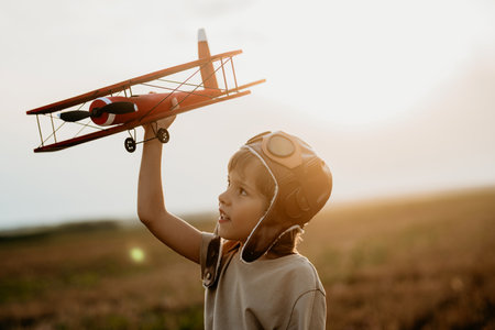 Handsome child boy running with wooden airplane. Kid dreaming to be pilot.