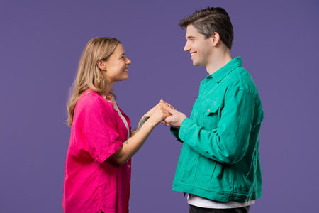 Love confession. Happy couple stands on violet, holding hands, look into eyes. Romantic feelings,...