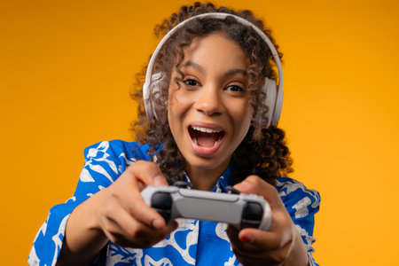 Young african woman playing and win online video game on console with joystickの写真素材