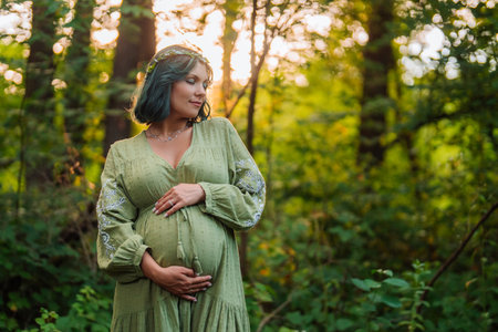 Pregnant Woman Carrying Child, Belly Close-Up, Forest Background. Expectant Timeの写真素材