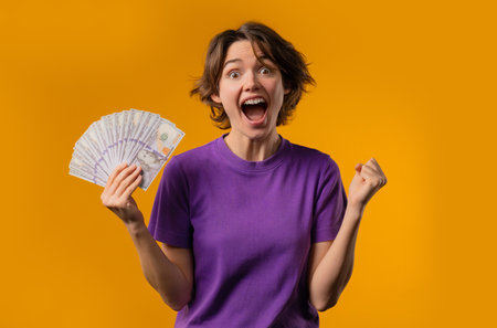 Amazed Woman With Money Cash. Happy Lady Got Usd Dollars Banknotes On Yellow