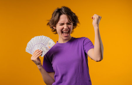 Amazed Woman With Money Cash. Happy Lady Got Usd Dollars Banknotes On Yellow