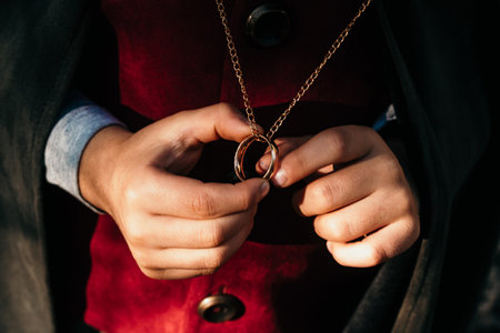 Unrecognizable child cosplayer in hobbit cape costume holding and wants to wear golden ring. Fantasy journey, halloween, fellowship cosplayの写真素材