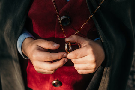 Unrecognizable child cosplayer in hobbit cape costume holding and wants to wear golden ring. Fantasy journey, halloween, fellowship cosplayの写真素材