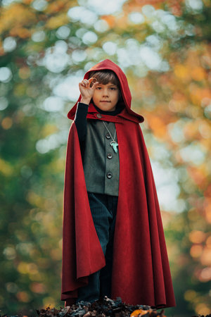 Cute cosplayer hobbit kid in cape costume in forest watching ring. Fantasy journey in fairytale wonderland, halloween, fellowship cosplayの写真素材