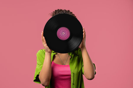 Young african woman hiding head or face with vinyl record disc. Hobby, Music Lover, Collectionの写真素材