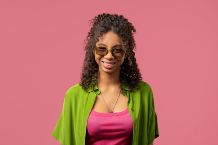 Young Charming African Woman in sunglasses eyewear With Kind Smile Looking To Camera On pink Studioの写真素材