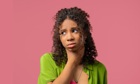 African teenage girl has sore. Woman with swollen throat on Pink studio.Anginaの写真素材