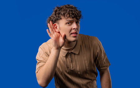 Curly man doesnt hear, asks what. Quiet whisper sound, deafness problemsの写真素材